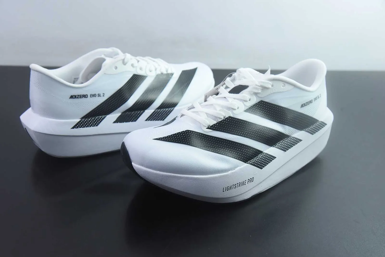 adidas Adizero Evo SL 2 na colorway Cloud White / Core Black (branco com as três riscas em preto e a inscrição "ADIZERO EVO SL 2")
