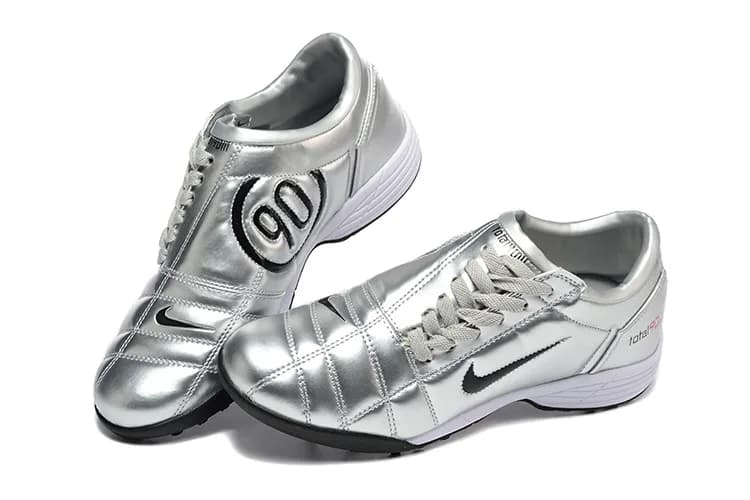 Nike Air Zoom Total 90 III TF (em tom prateado-metálico com pormenores em preto, logótipo "90" em destaque, sola intermédia branca e sola exterior preta).