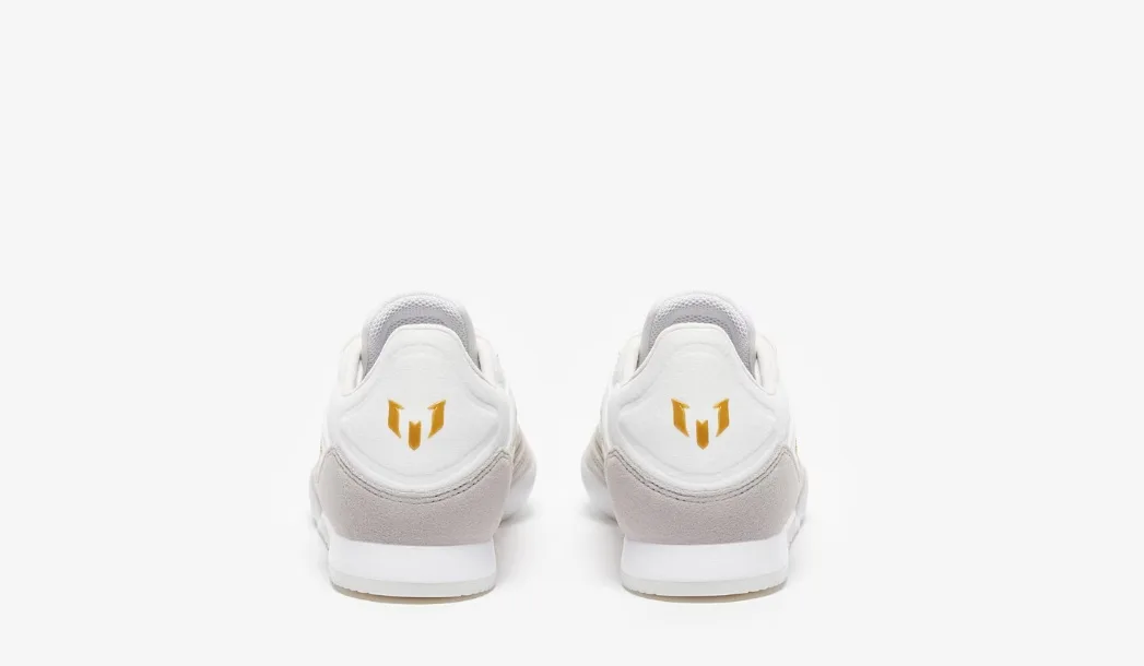 adidas F50 League IN (em tom branco e cinza-claro com as três riscas em dourado e sola branca).