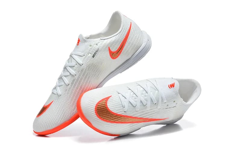 Nike Mercurial Vapor 14 Pro IC (em tom branco com pormenores em laranja e dourado/bronze e sola branca).