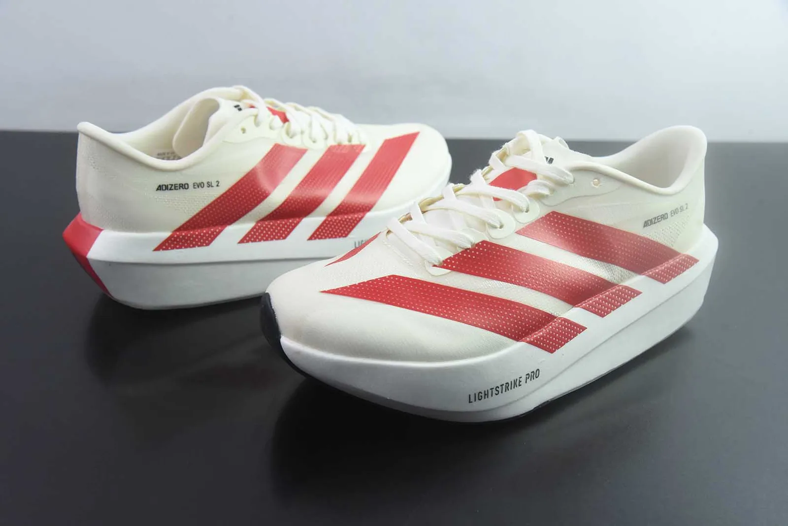 adidas Adizero Evo SL 2 na colorway Off White / Solar Red (branco/creme com as três riscas e pormenores no calcanhar em vermelho e a inscrição "ADIZERO EVO SL 2")
